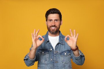 Wall Mural - Bearded man doing ok gesture on orange background