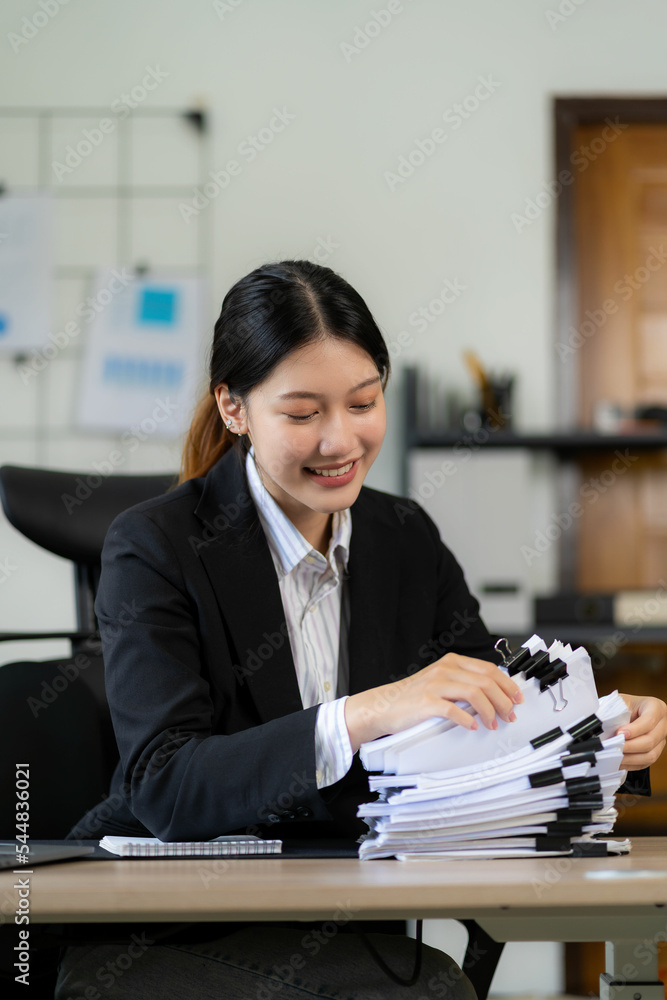 young asian woman working with piles of financial graph chart documents ...