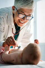 Wall Mural - Happy pediatrician doctor with baby checking possible heart defect