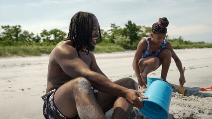 USA, Father and daughter playing on sandy beach