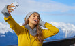 © ZoomTeam - technology and leisure concept - happy woman in winter fur hat taking selfie by smartphone outdoors