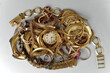 Old and broken jewelry, watches of gold, and gold-plated, and coins lies in a pile. A scrap of gold. Selective focus.