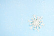 © Nastya - Beautiful decorative snowflake on white snow. blue background with space for text, greeting christmas card
