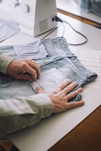 Hands Of Fashion Designer Adjusting Back Pocket On Jeans At Workshop