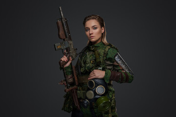 Portrait of apocalyptic female survivor holding rifle dressed in camouflage uniform.