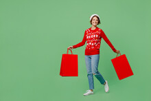 Full Body Young Woman Wear Knitted Xmas Sweater Santa Hat Hold Paper Package Bags After Shopping Isolated On Plain Solid White Color Background. Black Friday Sale Buy Day Happy New Year 202 Concept.
