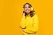© mary_markevich - smiling attractive woman listening to music in headphones on yellow background