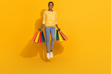 Canvas Print - Full length body size view of attractive trendy cheerful girl jumping holding bags isolated over bright yellow color background