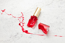 Red Broken Nail Polish Bottle On Marble Background, Dye Color Splash And Suffusion