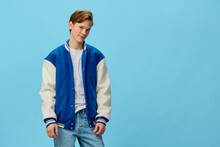 A Happy Guy In A White T-shirt And A Trendy Teen Bomber Jacket Stands Smiling Looking At The Camera On A Plain Background With Space For Text. Studio Photo