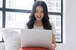 © kaew6566 - Happy asian casual woman reading news writing online with laptop or shopping comfortable at home. Freelance young girl using notebook relax, work sitting with pillow beside window.Lifestyle Technology