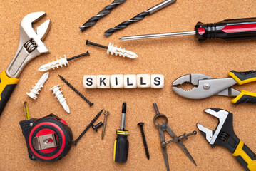 SKILLS word written on wood blocks. Various tools on cork background. business concept.