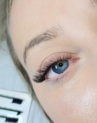 Close up of opened blue eye with eyelash Extensions in beauty salon macro eye