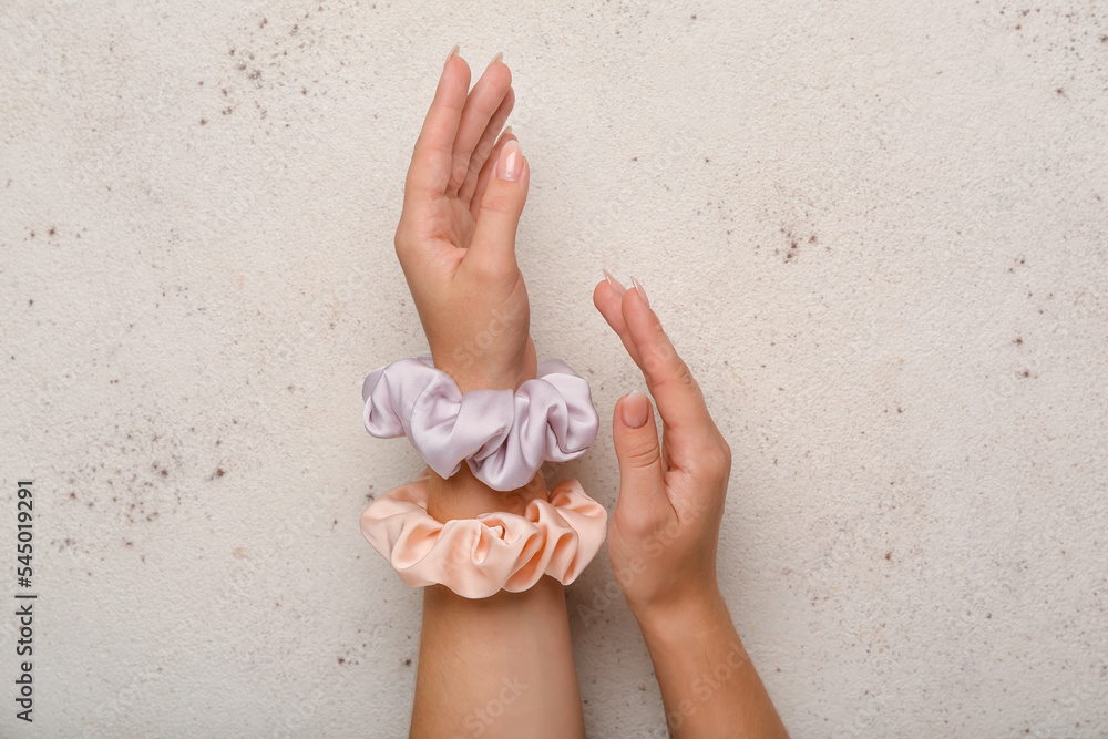 Female hands with scrunchies on light background