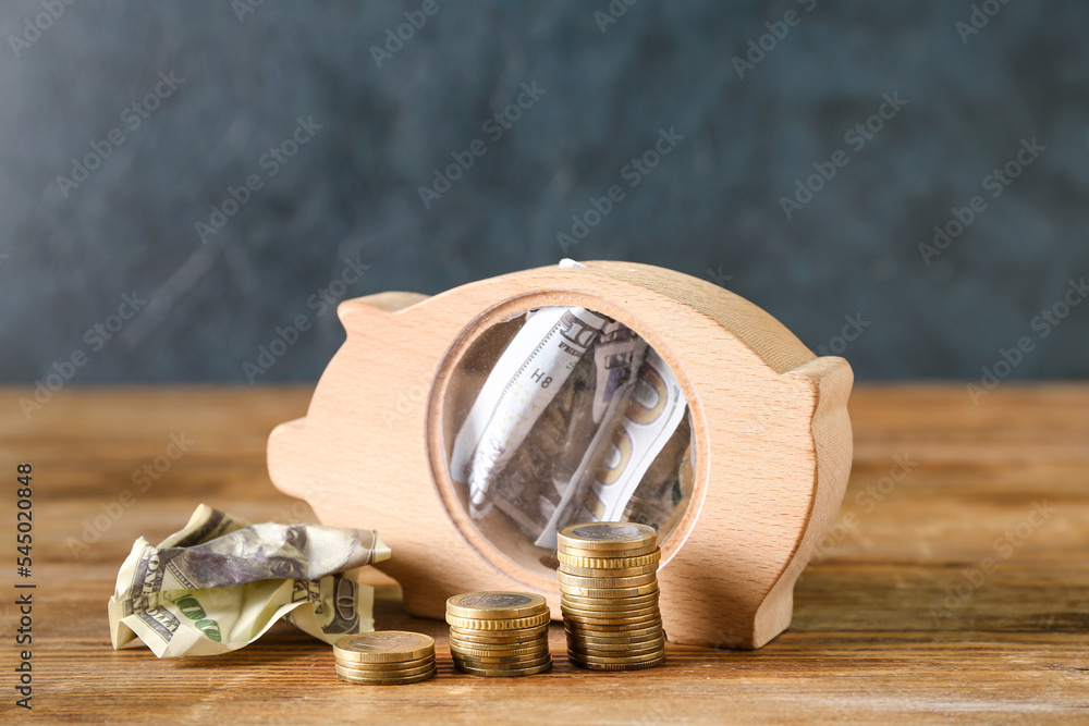 Piggy bank with money on table near dark wall. Budget concept
