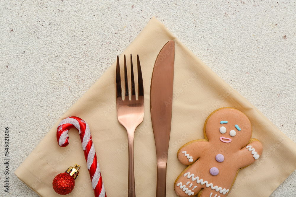 Napkin with cutlery, Christmas decorations and cookie on light background, closeup