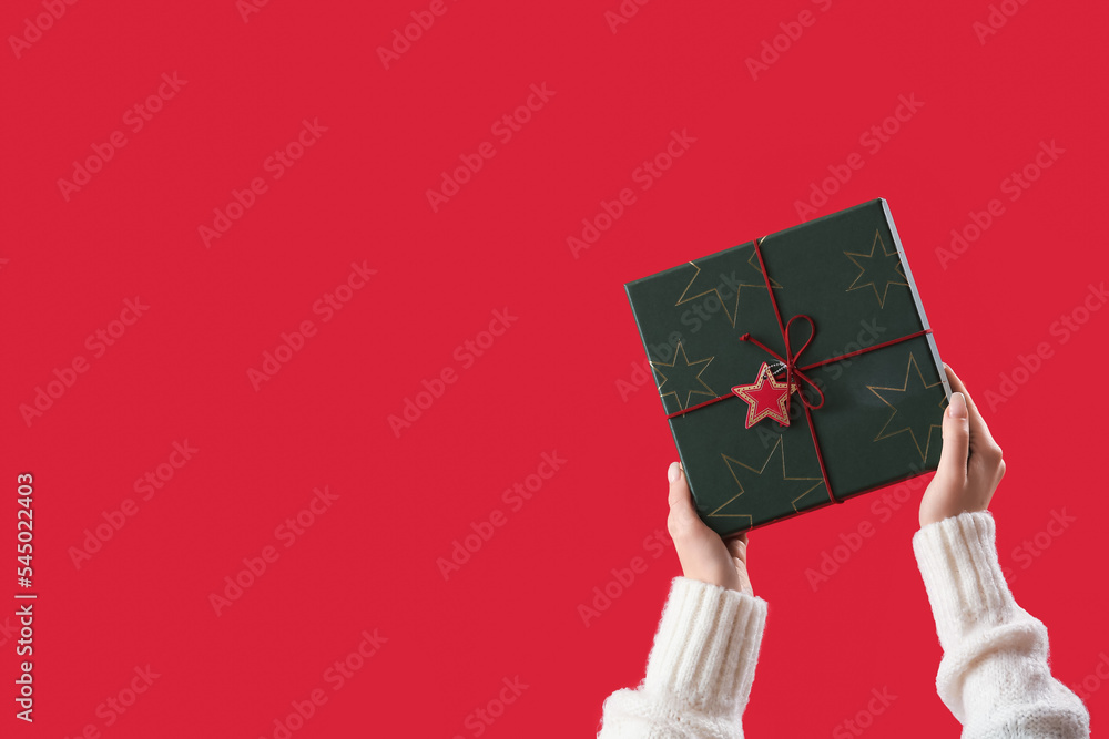 Woman with Christmas present on red background