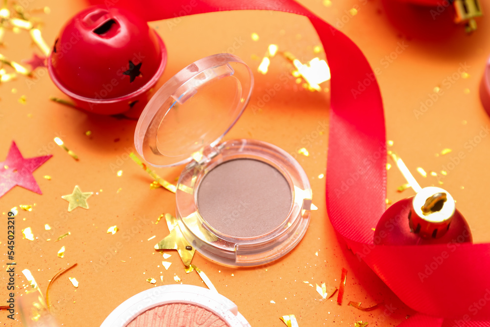Makeup product with Christmas decor on orange background