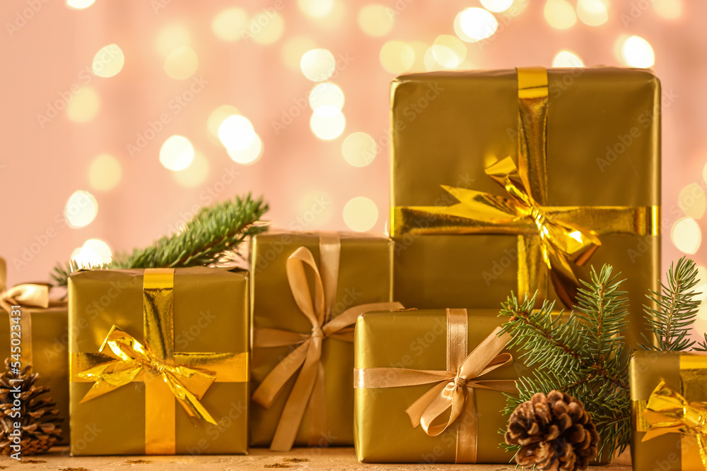 Many beautiful Christmas gifts on table against blurred lights, closeup