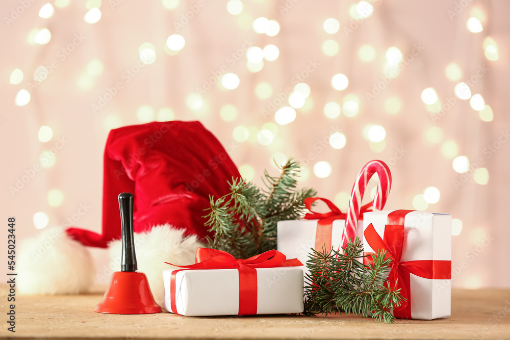 Christmas gifts, decor and fir branches on table against blurred lights