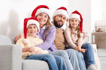 Sticker - Happy family in Santa hats sitting on sofa at home