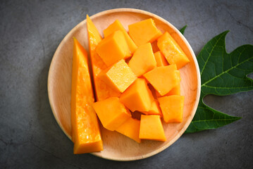 Wall Mural - papaya fruits on dark backgroud, fresh ripe papaya slice on plate tropical fruit with leaf leaves from papaya tree