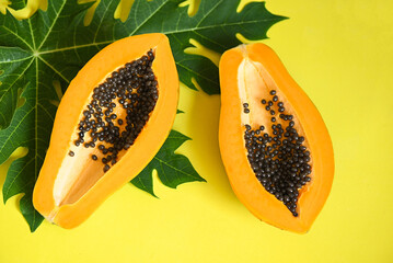 Wall Mural - papaya fruits on yellow backgroud, fresh ripe papaya slice tropical fruit with papaya seed and leaf leaves from papaya tree