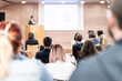 © kasto - Speaker giving a talk in conference hall at business event. Rear view of unrecognizable people in audience at the conference hall. Business and entrepreneurship concept