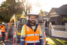 Man Road Worker With Beard Wearing White Hard Hat With High-vis Jacket During Evening Light