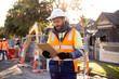 © Austockphoto - man road worker with beard and white hat wearing yellow jacket looking at his notes