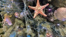New Year Decoration In Nautical Style. Seashells, Seahorse And Stars In The Design Of The Christmas Tree On A Blue Background. Starfish, Ribbons And Balls