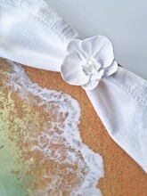 Epoxy Resin Sea Wave On The Sand Beach And White Napkin Ring. Top View, Table Setting