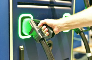 Electric car charger connector is held by a man in the charger