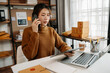 Portrait of Asian young woman SME working using smartphone or tablet taking receive and checking online purchase shopping order and delivery concept..