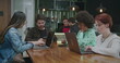 Group of people seated at coffee shop in front of laptop computers. Young millennials working or studying remotely using modern technology devices