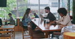 © Marco - Group of people inside coffee shop. Female friend handing espresso to male colleague sitting at cafe restaurant table. Men and women customers together at cafe place
