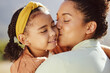 © S Fanti/peopleimages.com - Mother, child and kiss with smile for hug, love or care in family bonding, travel or summer break in the outdoors. Mama holding and kissing daughter for loving relationship or parenting in nature