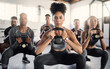 © N F/peopleimages.com - Fitness, kettle bell and gym class with a black woman coach training an athlete group in an exercise center. Workout, health and wellness with a man and woman team exercising in a sports facility