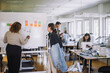 © Maskot - Rear view of fashion designer explaining female colleague while writing on whiteboard at workshop