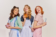 Portrait Of Beautiful, Cheerful Young Women, Housewives With Cooking Tools Isolated Over Grey Background. Pop Art