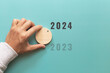 © sichon - Man hand choose number 2024 on blue background. countdown to 2024. Start concept