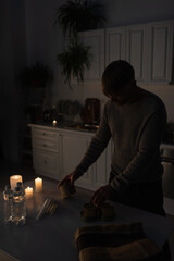 Wall Mural - man holding canned food near bottled water and candles in kitchen during power blackout.