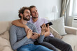 © Graphicroyalty - Young homosexual couple relaxing on sofa in the living room, embracing and enjoying while watching TV