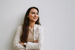 © Drobot Dean - Young indian woman smiling and looking aside while standing by wall