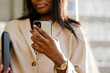 © Drobot Dean - Young black businesswoman using cellphone while walking outdoors