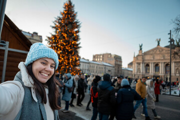 Wall Mural - beautiful smiling women taking selfie picture at city square christmas tree on background