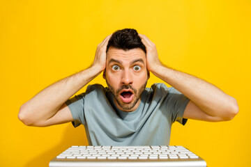 Closeup photo of young crazy smart it developer excited touching head unexpected bad news inflation economics use keyboard isolated on yellow color background