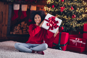 Wall Mural - Photo of pretty adorable cheerful child teenager sitting floor cozy xmas interior room home house enjoy magic time rejoice hold package