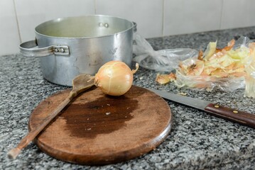 Wall Mural - Closeup of cooking items- a wooden spoon, a knife and an onion on a wooden board