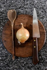 Wall Mural - Closeup of cooking items- a wooden spoon, a knife and an onion on a wooden board